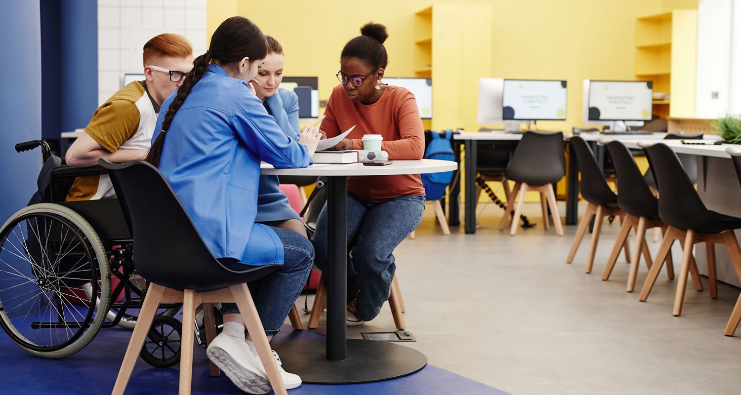 Group of diverse student s sat at table looking at notes