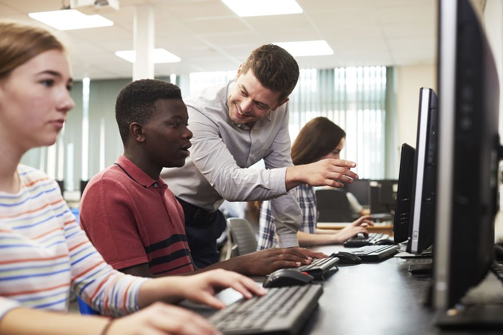 Students working on computers guided by teacher